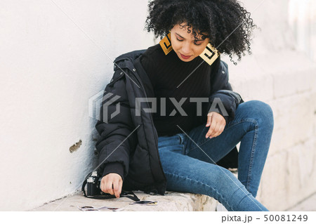 Young woman sorting photographs on bench 50081249
