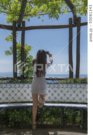 Woman taking photograph with smart phone under pergola Woman taking photograph with smart phone under pergola 50081343
