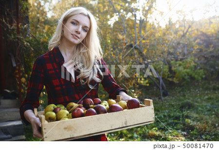 Young woman holding crate of apples Young woman holding crate of apples 50081470