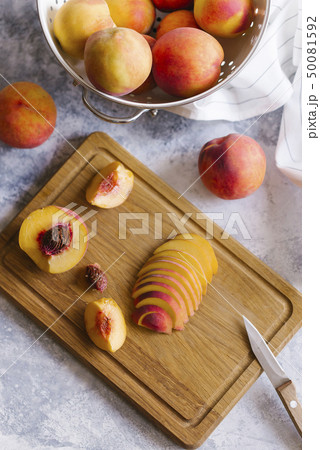 Peaches sliced on wooden cutting board 50081592