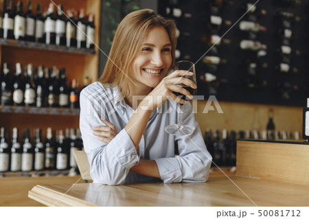 Smiling young woman holding glass of red wine 50081712