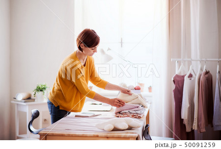 Young creative woman in a studio, startup of small tailoring business. 50091259