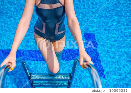 A woman getting out of the blue water in the pool. A woman getting out of the blue water in the pool. 50096031