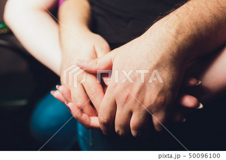Close up male and female holding hands over table. 50096100