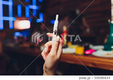 heat-not-burn tobacco product technology. Woman holding e-cigarette in his hand before smoking. heat-not-burn tobacco product technology. Woman holding e-cigarette in his hand before smoking. 50096834
