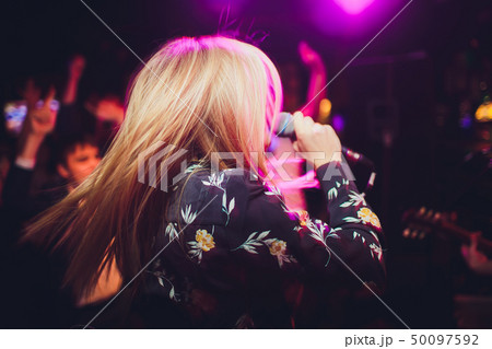 Beauty model girl singer with a microphone singing and dancing over holiday glowing background 50097592