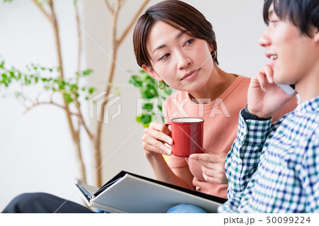 ソファでくつろぐ夫婦　通話内容が気になる 50099224