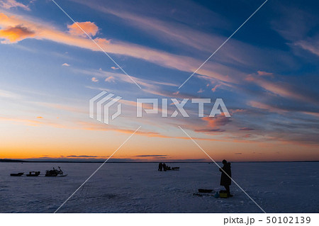 silhouettes of a fisherman with a fishing rod on a winter fishing 50102139