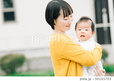 赤ちゃんを抱く若い母親 日本人親子 中庭の写真素材