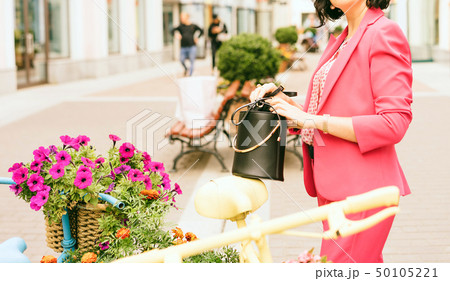 A woman in fashionable clothes holds in hands a black handbag. A woman in fashionable clothes holds in hands a black handbag. 50105221