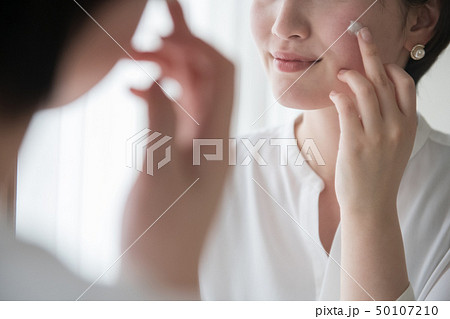 顔に日焼け止めクリームを塗る若い日本人女性 50107210