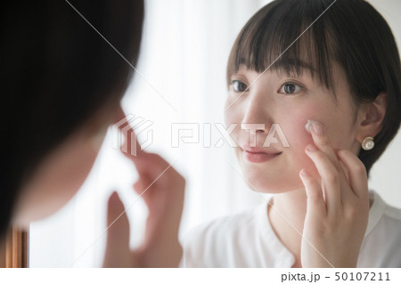 顔に日焼け止めクリームを塗る若い日本人女性 50107211