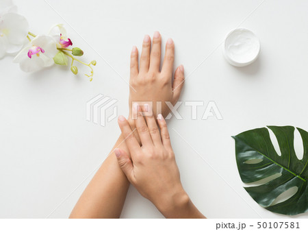 Woman putting cream on her hands on white background Woman putting cream on her hands on white background 50107581