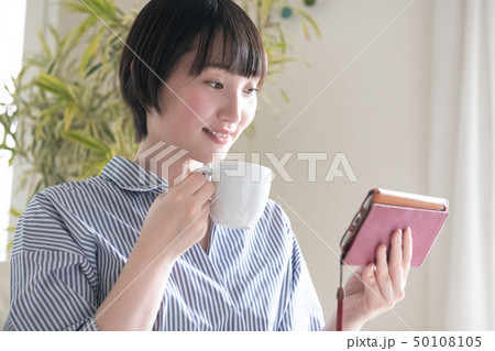 スマホを見ながらコーヒーを飲む若い日本人女性 スマホを見ながらコーヒーを飲む若い日本人女性 50108105
