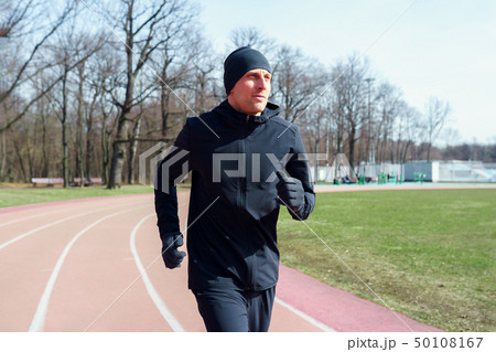 Photo of young athlete man running through stadium during spring jog . 50108167
