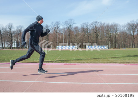 Photo on side of athlete man running through stadium during spring jog 50108198