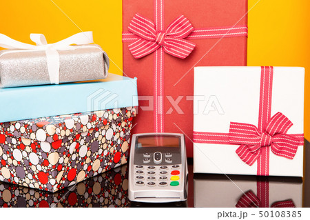 Terminal, boxes with gifts on black glass table and yellow background. 50108385