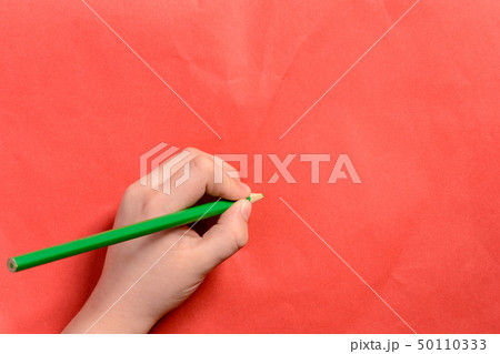 The hand of a young boy holds a green pencil on a The hand of a young boy holds a green pencil on a 50110333