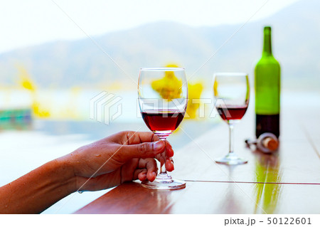 Man holding and drinking red wine while swimming 50122601