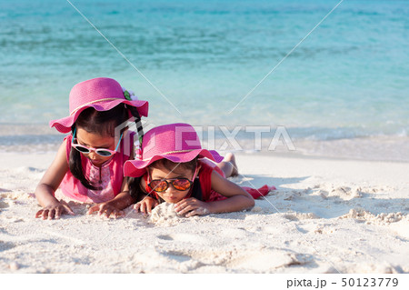 Two asian girls playing with sand on the beach 50123779