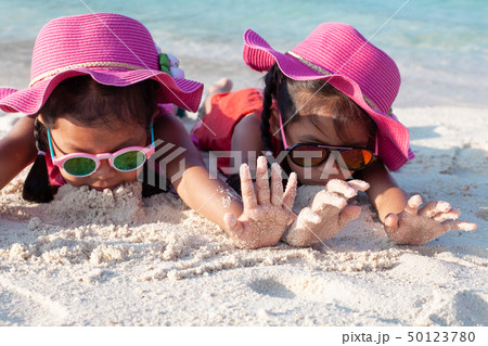 Two asian girls playing with sand on the beach 50123780