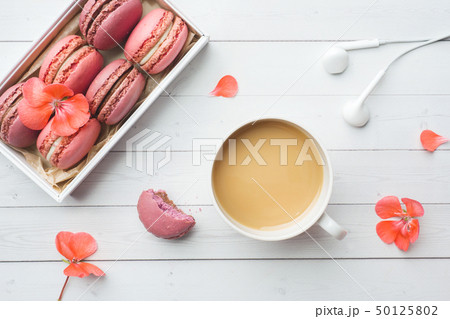 Cup of coffee, macaroon cookies in a box, flowers  50125802