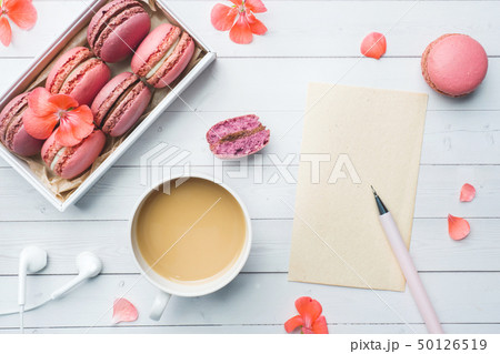 Cup of coffee, macaroon cookies in a box, flowers  50126519