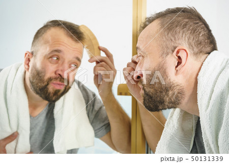Man using comb in bathroom 50131339