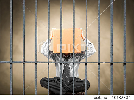 man sitting behind the bars of a prison 50132384
