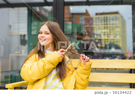 A long-haired, cheerful blonde girl combs her hair 50134422