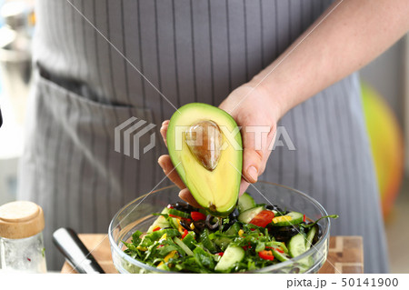 Male Hand Holding Oiled Tropical Avocado Half 50141900