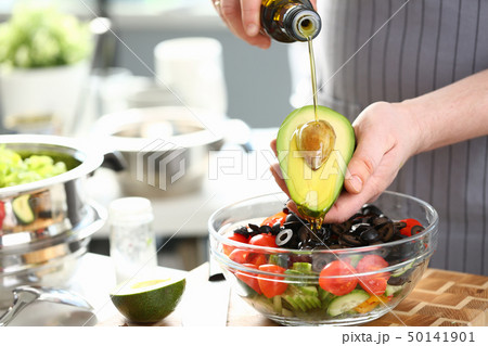 Male Hands Pouring Oil Halved Tropical Avocado 50141901