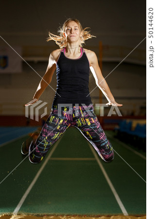 Young sportswoman flying in long jump attempt Young sportswoman flying in long jump attempt 50144620