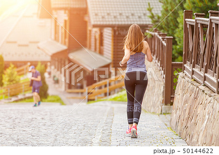 Back view of running woman on cobbled road with copy space aside Back view of running woman on cobbled road with copy space aside 50144622