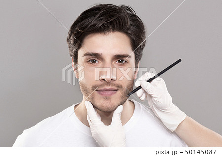 Beautician hands marking male face before beauty operation Beautician hands marking male face before beauty operation 50145087