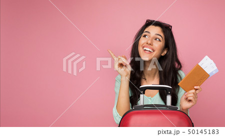 Happy girl with tickets pointing finger away 50145183
