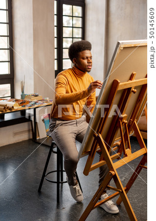 Nice talented man sitting in front of his painting 50145609
