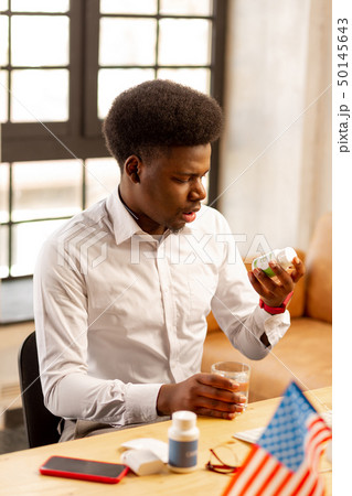 Nice handsome man looking at the bottle with pills 50145643