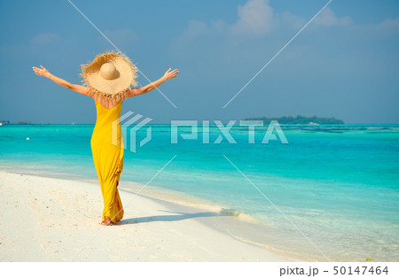 Woman in dress walking on tropical beach 50147464