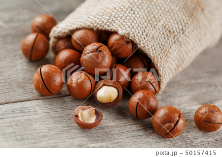 Macadamia nut on a wooden table in a bag, closeup, 50157415