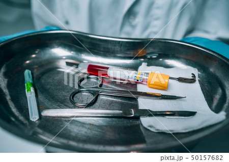 Nurse in rubber gloves holding a tray of surgical medical equipment 50157682