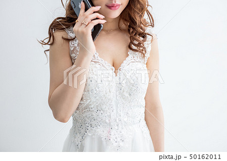 白背景に白いレースのドレスを着た美脚の女性が携帯電話を持っているモデル美人綺麗キャバクラキャバ嬢 50162011