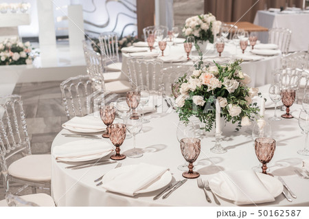 Flower arrangement in the center of the table. Interior of restaurant for wedding dinner, ready for 50162587