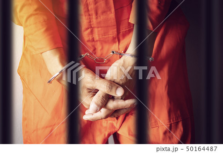 prisoner hands in handcuffs behind the jail bars 50164487