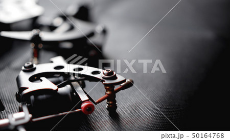 Tattoo machine and tattoo supplies on dark background 50164768