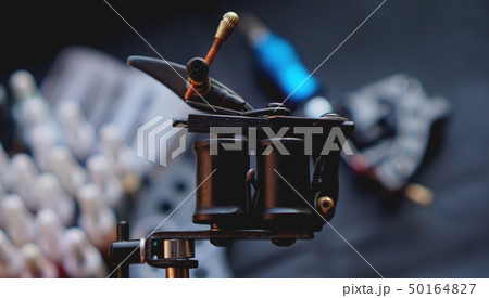 Tattoo machine and tattoo supplies on dark background Tattoo machine and tattoo supplies on dark background 50164827