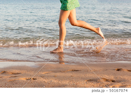 Leg of woman running on beach with water Leg of woman running on beach with water 50167074