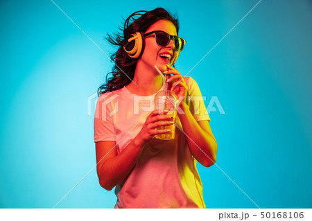 Happy young woman standing and smiling against blue background 50168106