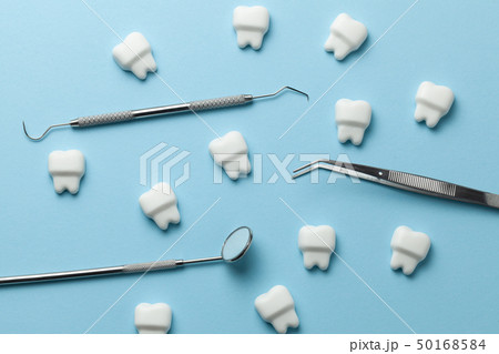 Healthy white teeth on blue background and dentist tools mirror, hook. 50168584