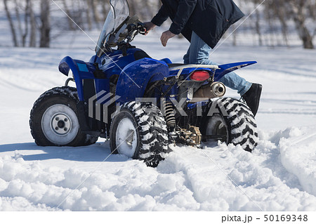 A person riding a bright blue snowmobile in the forest. Back view 50169348